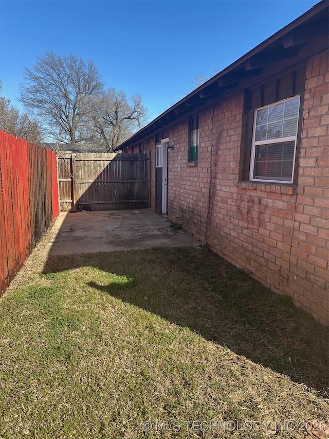 view of property exterior with brick siding, a patio area, a lawn, and a fenced backyard