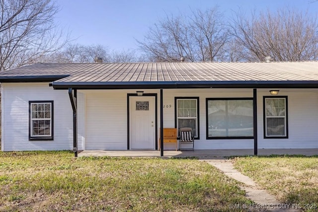 view of front facade with metal roof, a porch, and a front lawn