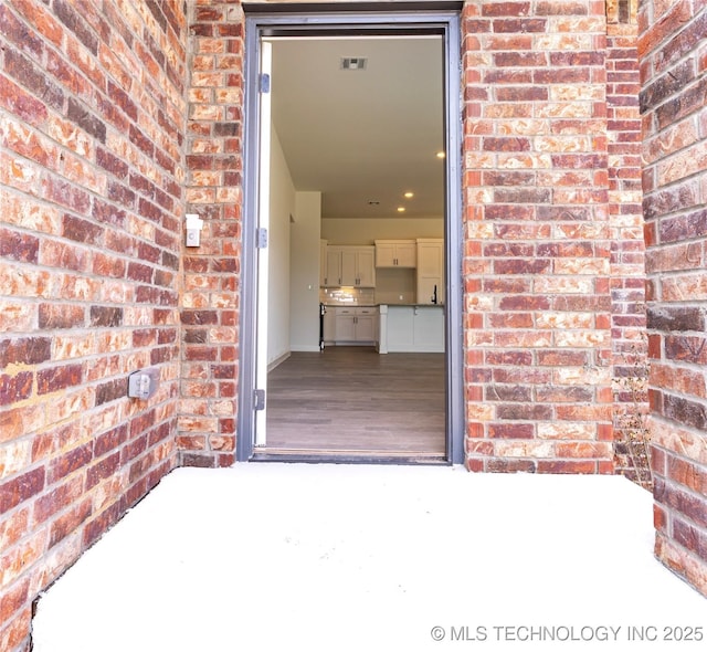 doorway to property featuring brick siding