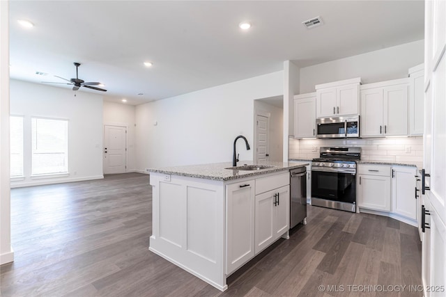 kitchen with visible vents, decorative backsplash, dark wood-type flooring, stainless steel appliances, and a sink