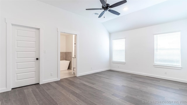 unfurnished bedroom with vaulted ceiling, multiple windows, wood finished floors, and baseboards