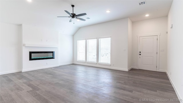 unfurnished living room with wood finished floors, a glass covered fireplace, visible vents, and a ceiling fan