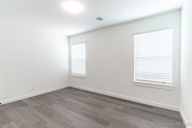 spare room featuring baseboards, visible vents, and dark wood-style flooring