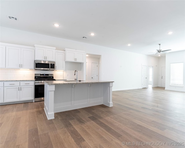 kitchen with visible vents, decorative backsplash, light wood-style flooring, stainless steel appliances, and a sink