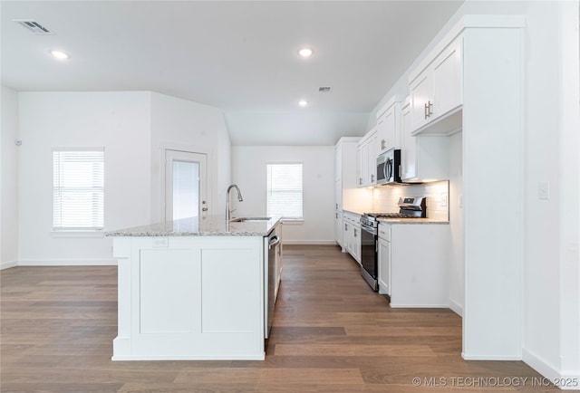 kitchen featuring visible vents, appliances with stainless steel finishes, wood finished floors, a kitchen island with sink, and a sink