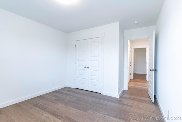 unfurnished bedroom with a closet, baseboards, and wood finished floors