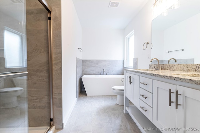 bathroom featuring toilet, a sink, visible vents, a shower stall, and double vanity