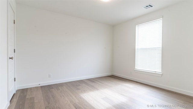 unfurnished room with plenty of natural light, light wood-style flooring, visible vents, and baseboards