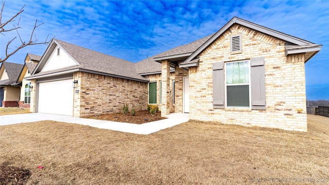 view of front of house featuring brick siding, a shingled roof, a front yard, a garage, and driveway