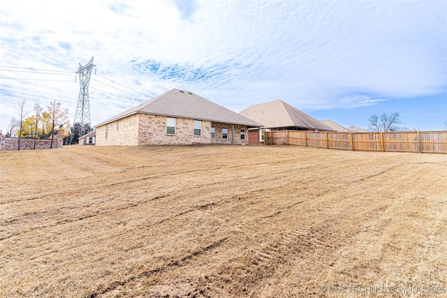 rear view of house featuring brick siding and fence