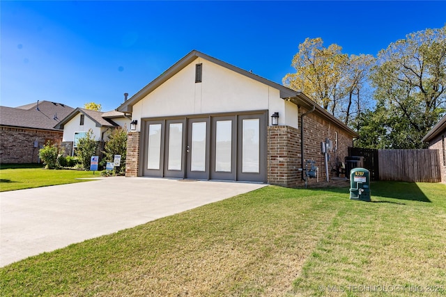 view of front of property with stucco siding, fence, a front lawn, and brick siding