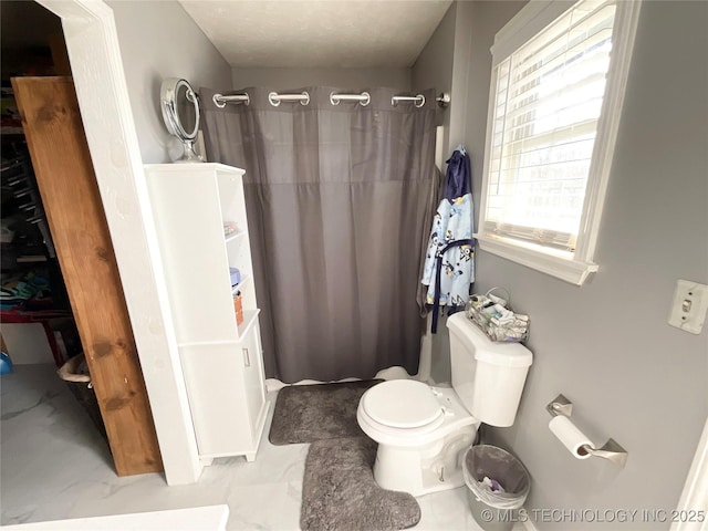 full bath featuring curtained shower, marble finish floor, and toilet