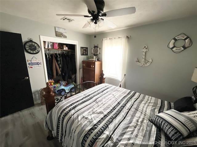 bedroom featuring ceiling fan, a closet, wood finished floors, and visible vents