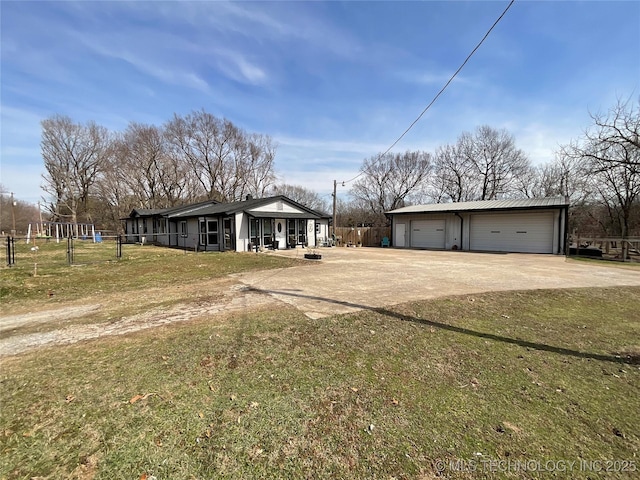 view of front of home featuring an outbuilding, metal roof, a front lawn, and a detached garage