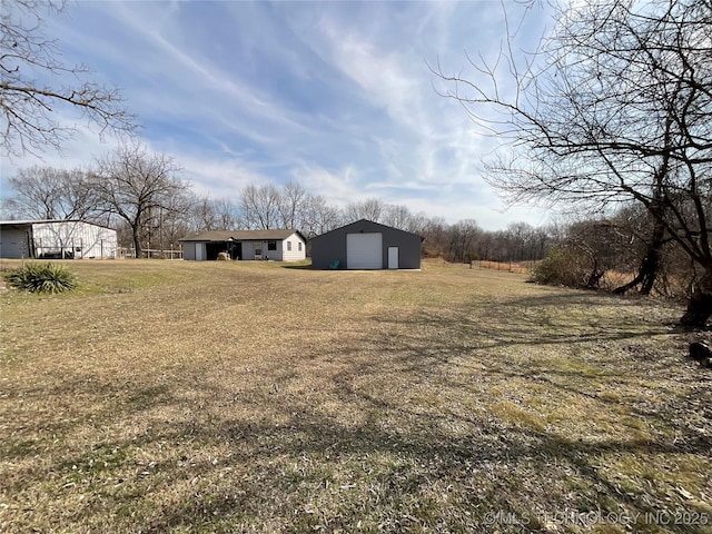 view of yard featuring a garage, driveway, and an outdoor structure