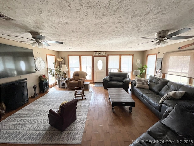 living area with visible vents, ceiling fan, a textured ceiling, and wood finished floors