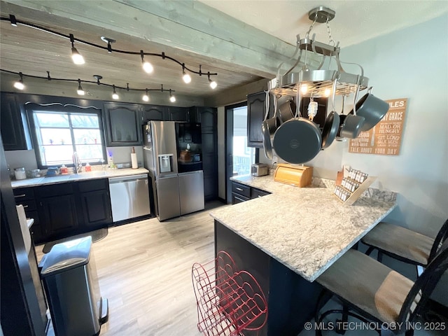 kitchen featuring a breakfast bar area, a peninsula, light countertops, appliances with stainless steel finishes, and light wood-type flooring