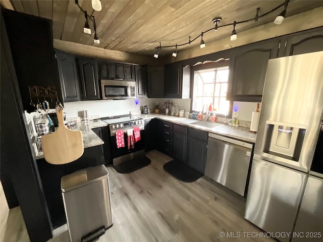 kitchen featuring light wood finished floors, light countertops, appliances with stainless steel finishes, wood ceiling, and a sink