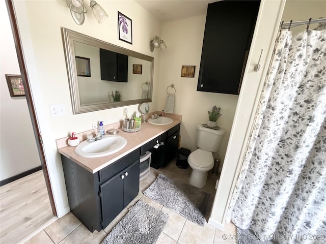 bathroom with toilet, tile patterned flooring, double vanity, and a sink