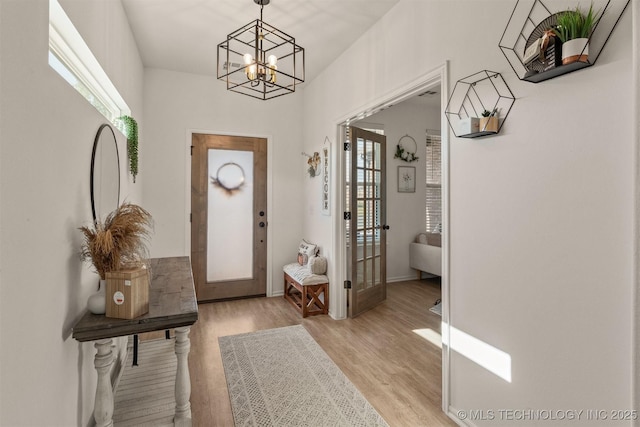 entryway featuring light wood-style floors, french doors, and an inviting chandelier