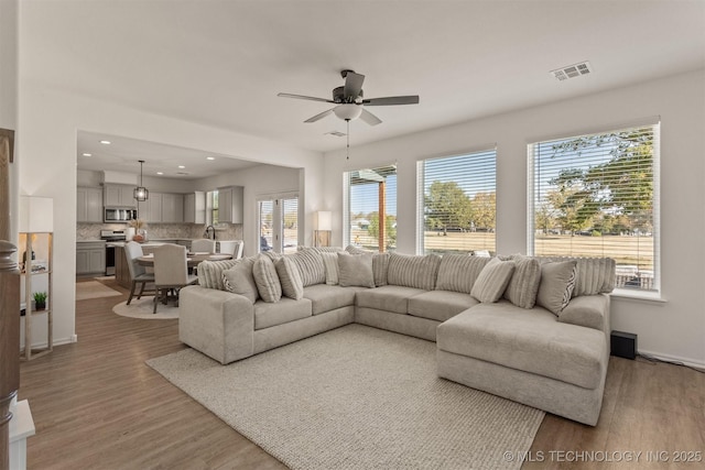 living area featuring baseboards, visible vents, ceiling fan, wood finished floors, and recessed lighting