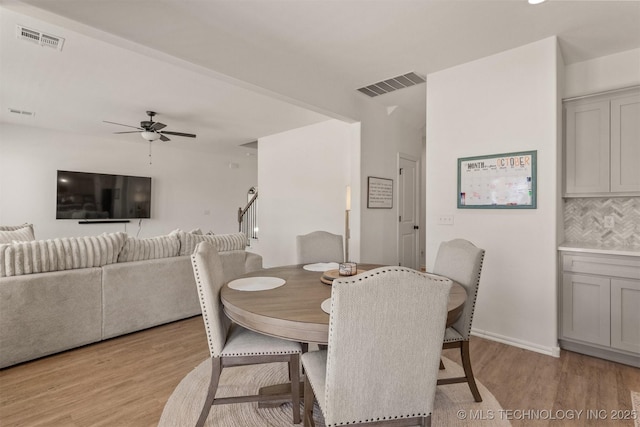 dining area featuring light wood finished floors, stairway, and visible vents