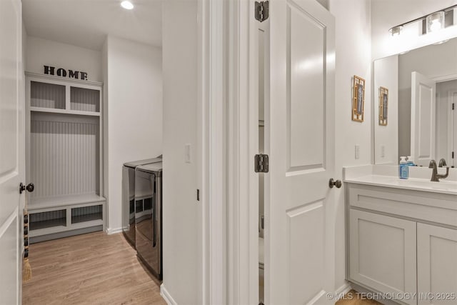 interior space with a sink, laundry area, light wood finished floors, and washer and dryer