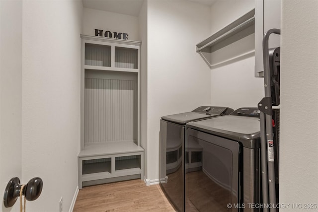 clothes washing area featuring laundry area, baseboards, wood finished floors, and washing machine and clothes dryer