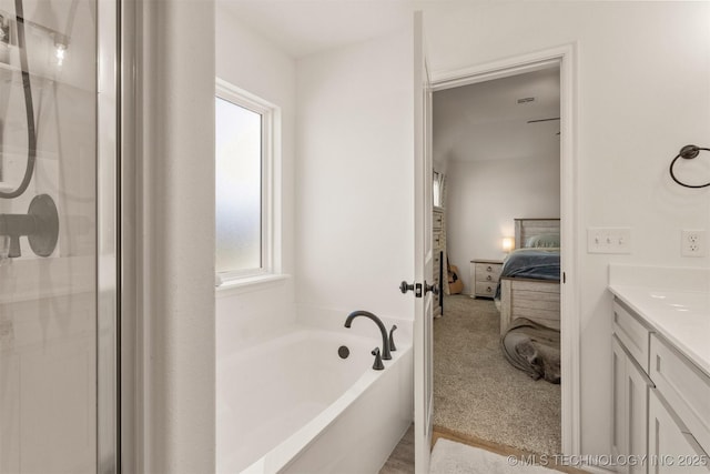 ensuite bathroom with a shower with door, ensuite bath, a garden tub, and vanity