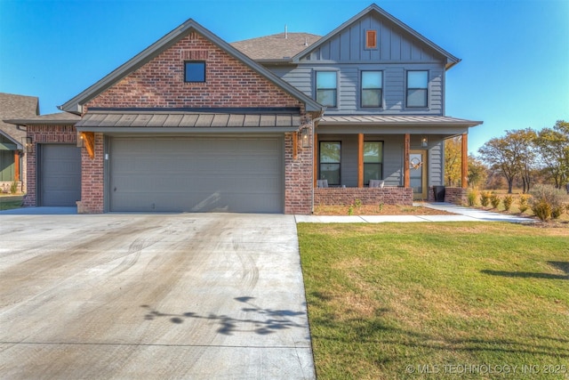 view of front of house with brick siding, board and batten siding, a front yard, a standing seam roof, and a garage