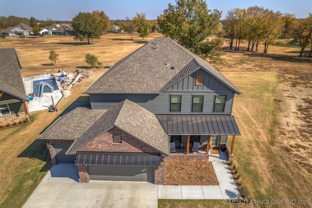 view of front of house with a porch, a shingled roof, board and batten siding, a standing seam roof, and driveway