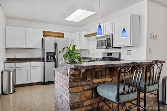 kitchen with dark countertops, a kitchen breakfast bar, decorative light fixtures, a peninsula, and stainless steel appliances