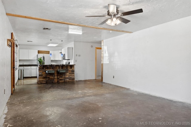 unfurnished living room with ceiling fan, concrete floors, visible vents, and a textured ceiling