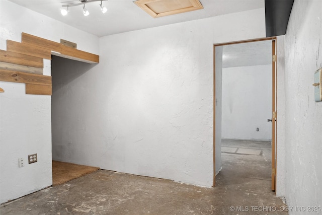 empty room with attic access and unfinished concrete floors