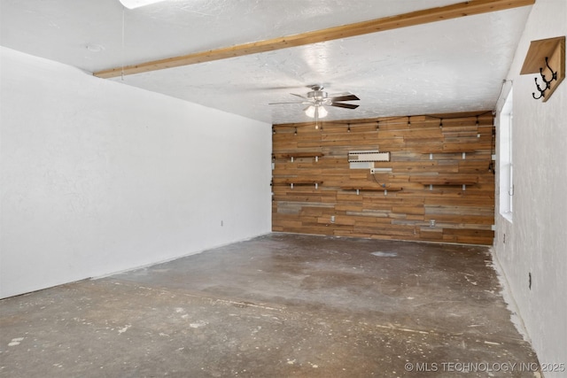 unfurnished room featuring unfinished concrete floors, ceiling fan, and wooden walls