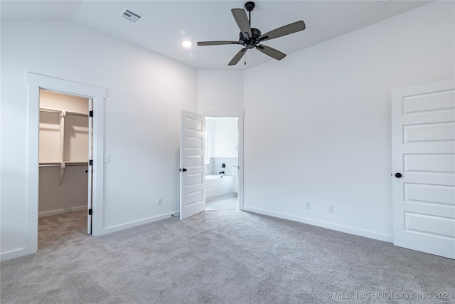 unfurnished bedroom with recessed lighting, carpet floors, baseboards, vaulted ceiling, and a walk in closet