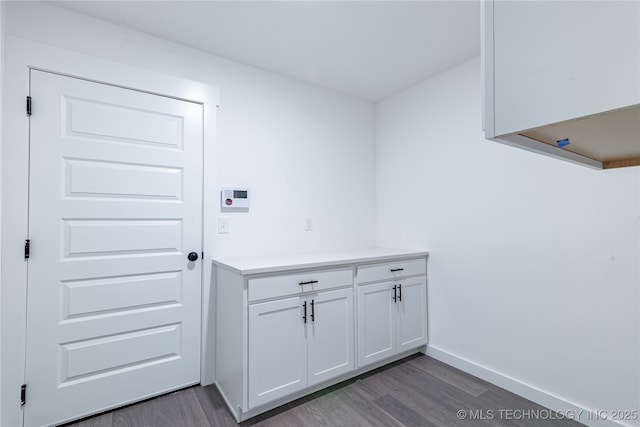 clothes washing area with baseboards and wood finished floors