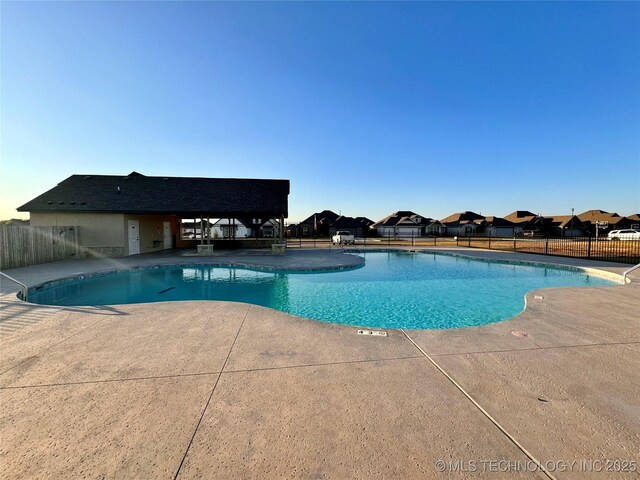 pool with a residential view, a patio area, and fence