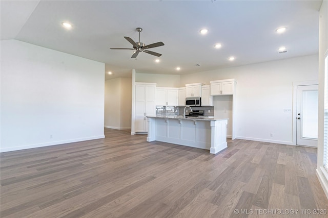 kitchen featuring open floor plan, stainless steel appliances, backsplash, and white cabinetry