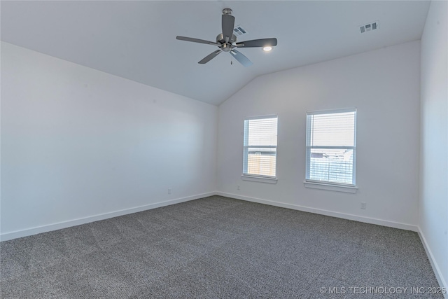 spare room with ceiling fan, visible vents, baseboards, vaulted ceiling, and dark colored carpet