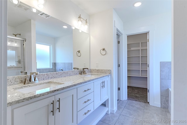 bathroom with visible vents, a sink, and a shower stall