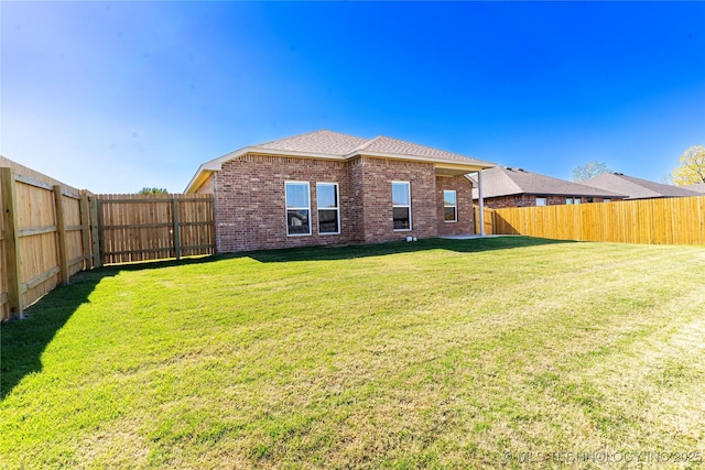 rear view of property with brick siding, a lawn, and a fenced backyard