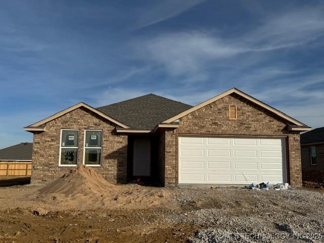 single story home featuring brick siding, an attached garage, and roof with shingles