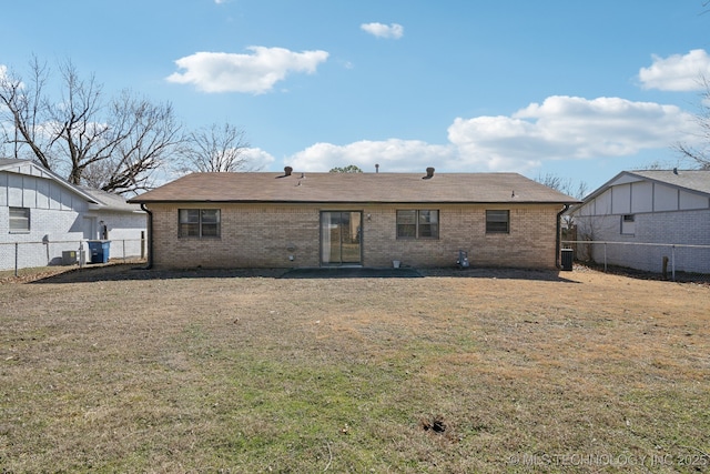 rear view of house featuring a yard, brick siding, and a fenced backyard