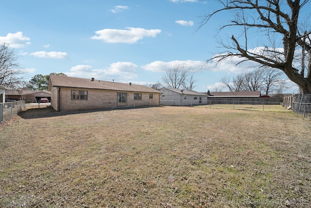 back of property featuring brick siding, a lawn, and a fenced backyard