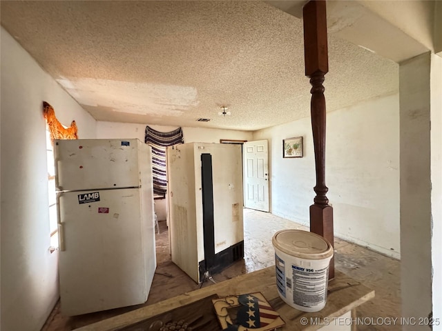 kitchen with a textured ceiling and freestanding refrigerator