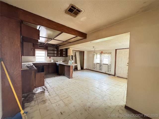 kitchen with a wealth of natural light, visible vents, a textured ceiling, and light floors