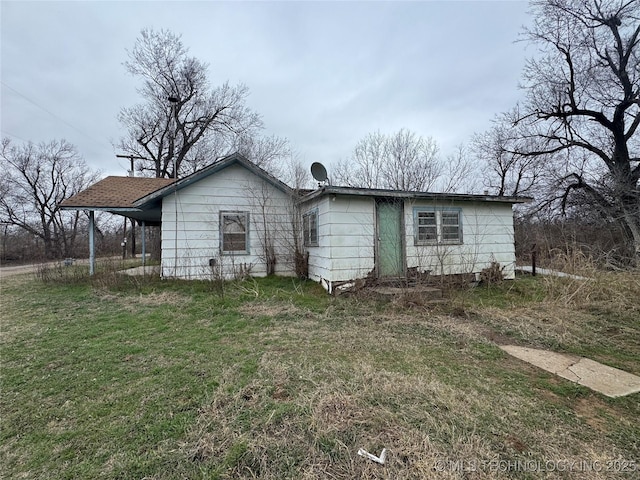 rear view of property featuring a yard and an attached carport