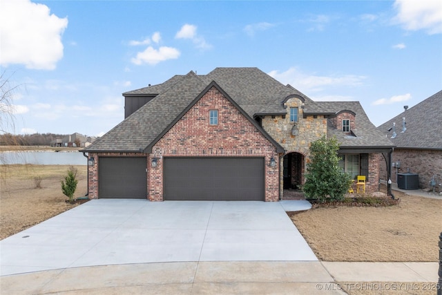 french provincial home with driveway, brick siding, and roof with shingles