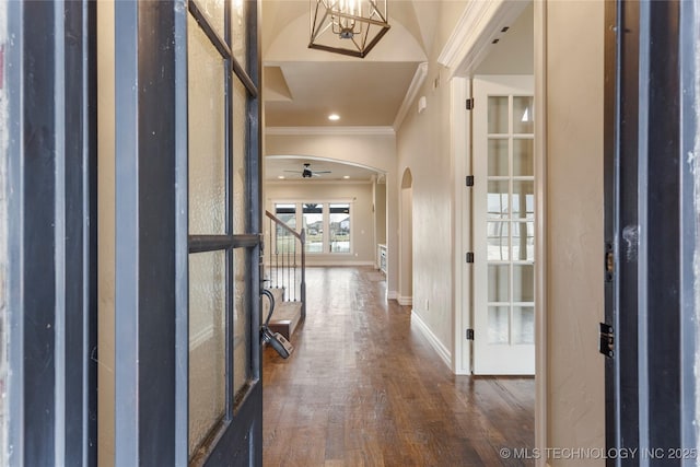 entrance foyer featuring arched walkways, baseboards, stairway, dark wood finished floors, and crown molding